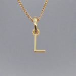 Gold necklace with a 'L' pendant on a gray background