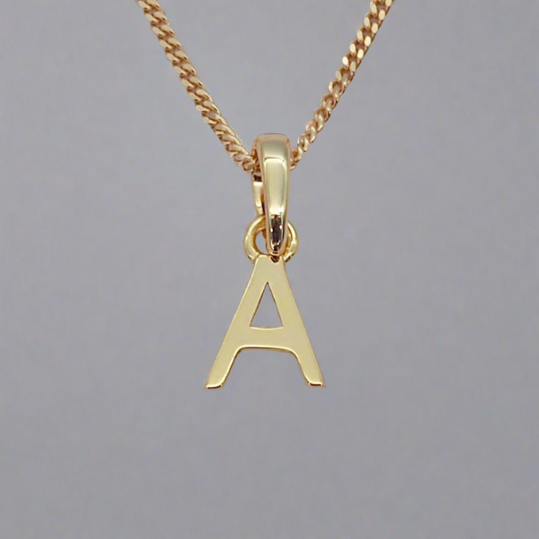 gold initial 'a' pendant necklace on a grey background