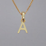 gold initial 'a' pendant necklace on a grey background