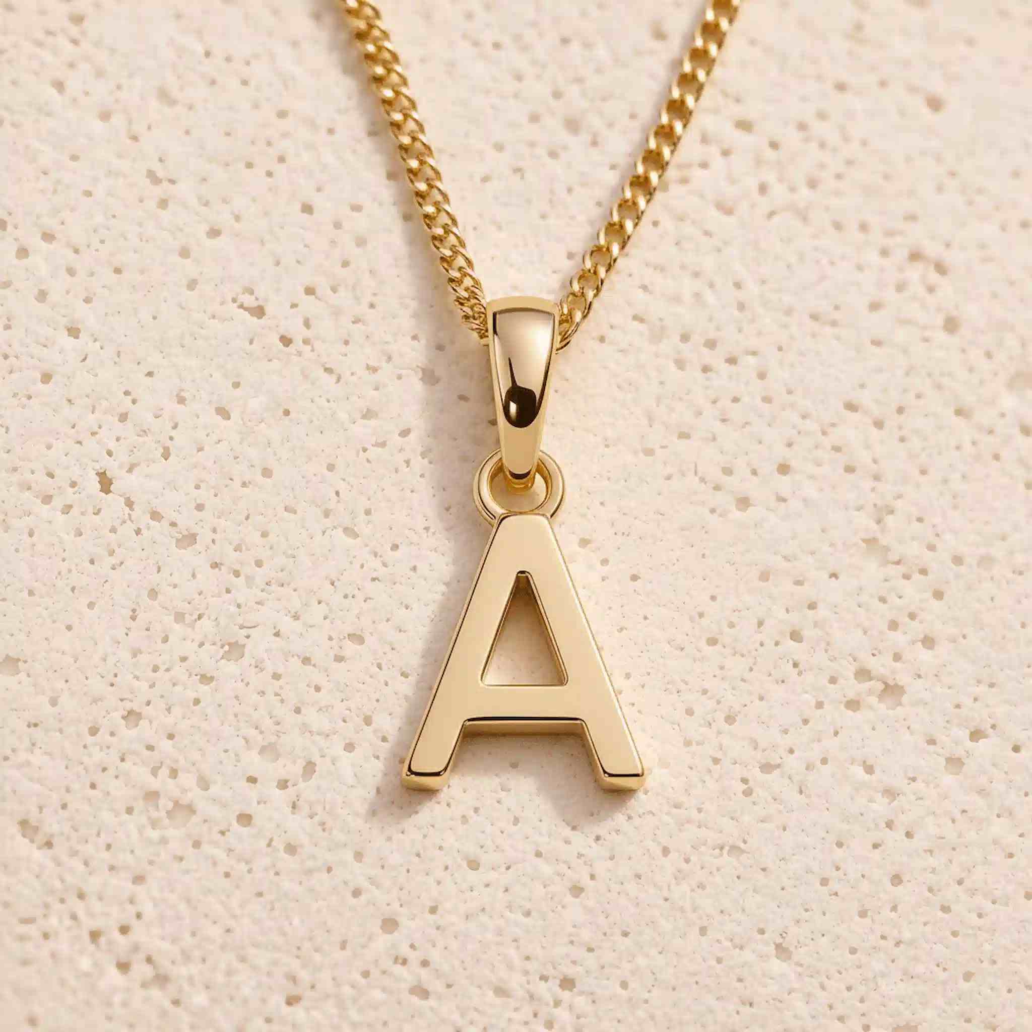 gold initial 'a' pendant necklace on a grey background
