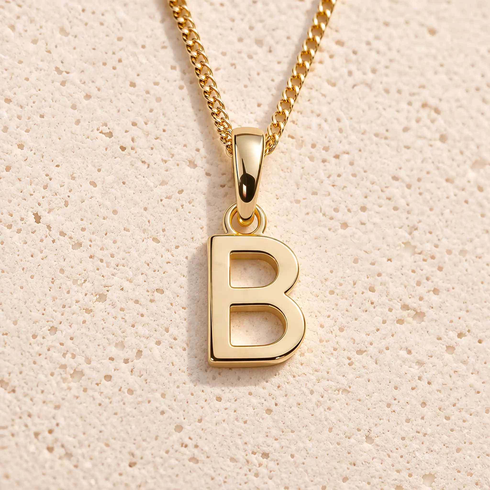 gold initial 'B' pendant necklace on a grey background