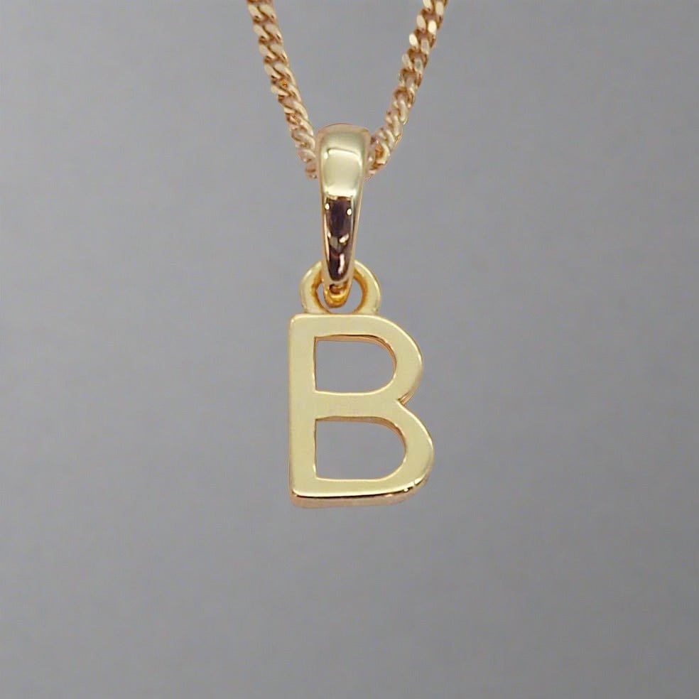 gold initial 'B' pendant necklace on a grey background