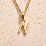 Close-up of gold initial necklace with a N letter charm on a fine gold chain; a letter charm option to personalise Necklaces