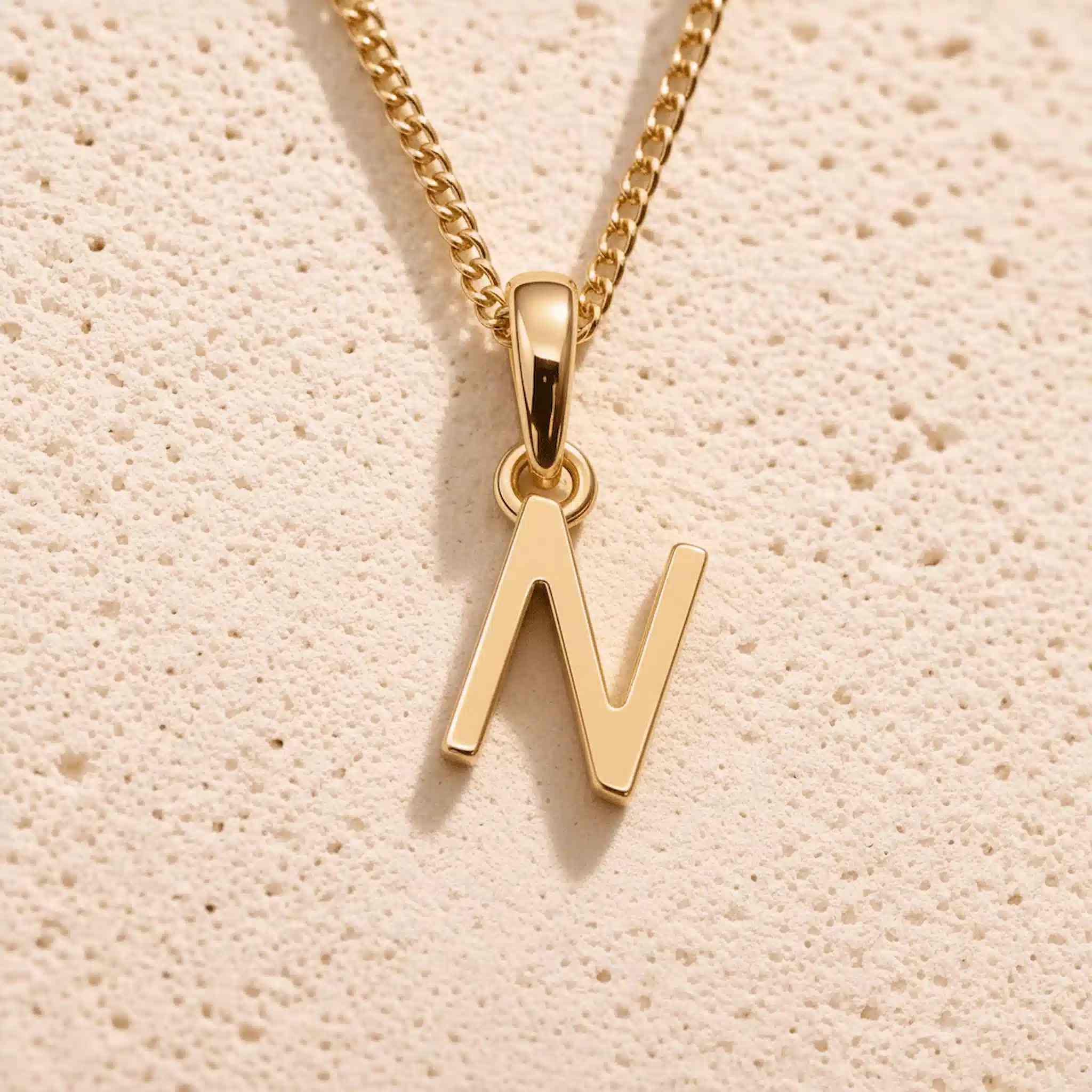Close-up of gold initial necklace with a N letter charm on a fine gold chain; a letter charm option to personalise Necklaces