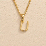 Close-up of gold initial necklace with a  U letter charm on a fine gold chain; a letter charm option to personalise Zodiac and Birthstone Necklaces