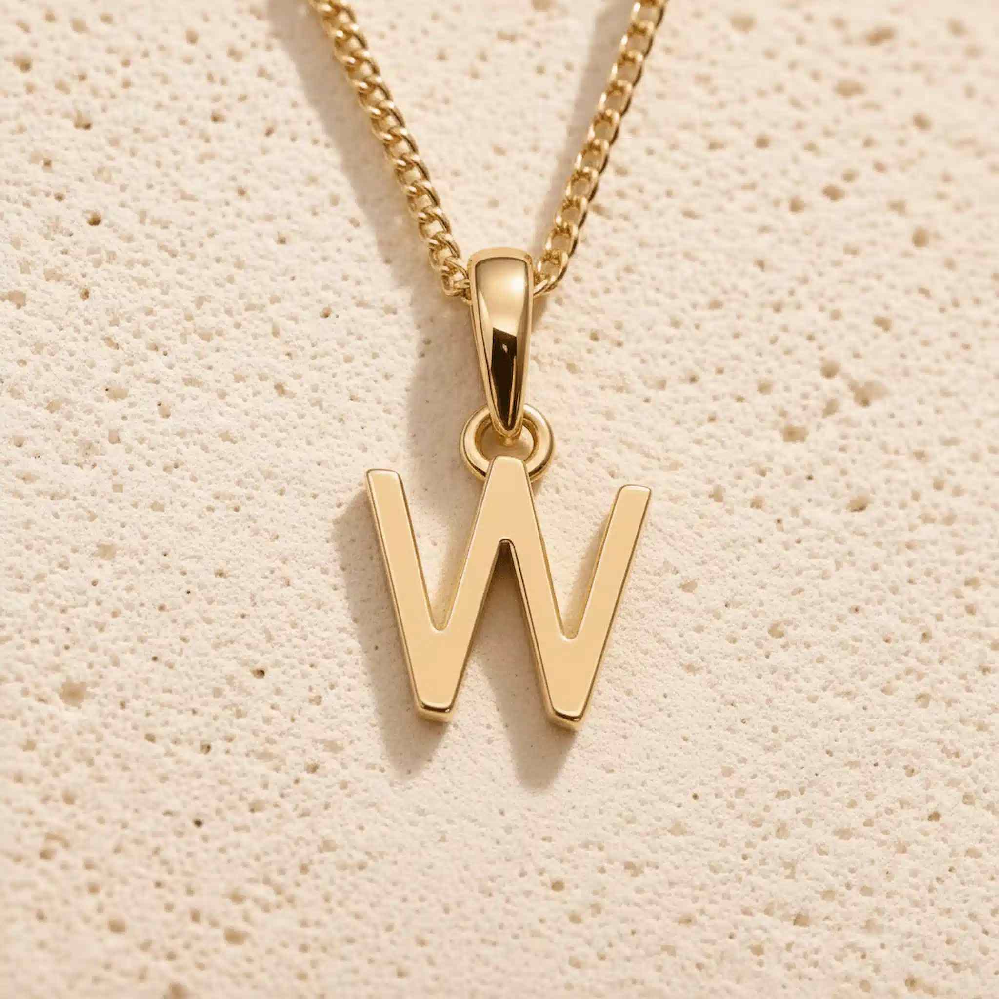 Close-up of gold initial necklace with a  W letter charm on a fine gold chain; a letter charm option to personalise Zodiac and Birthstone Necklaces