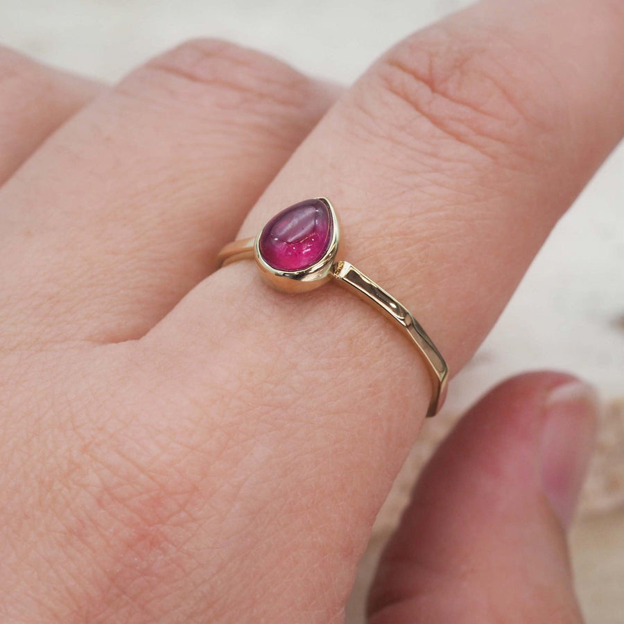 Woman wearing January birthstone ring in gold and made with garnet 