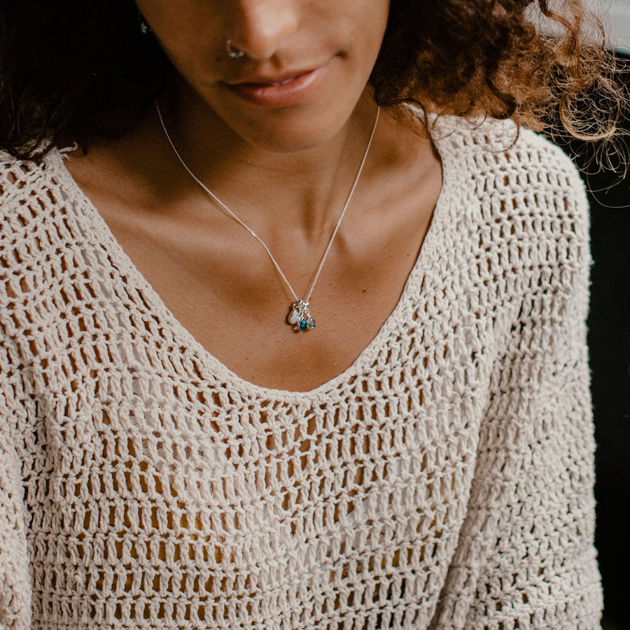 Woman wearing multiple birthstone pendants on a sterling silver chain necklace