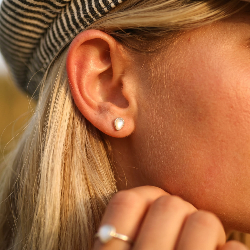 Woman with blonde hair wearing gold June birthstone mother of pearl earrings