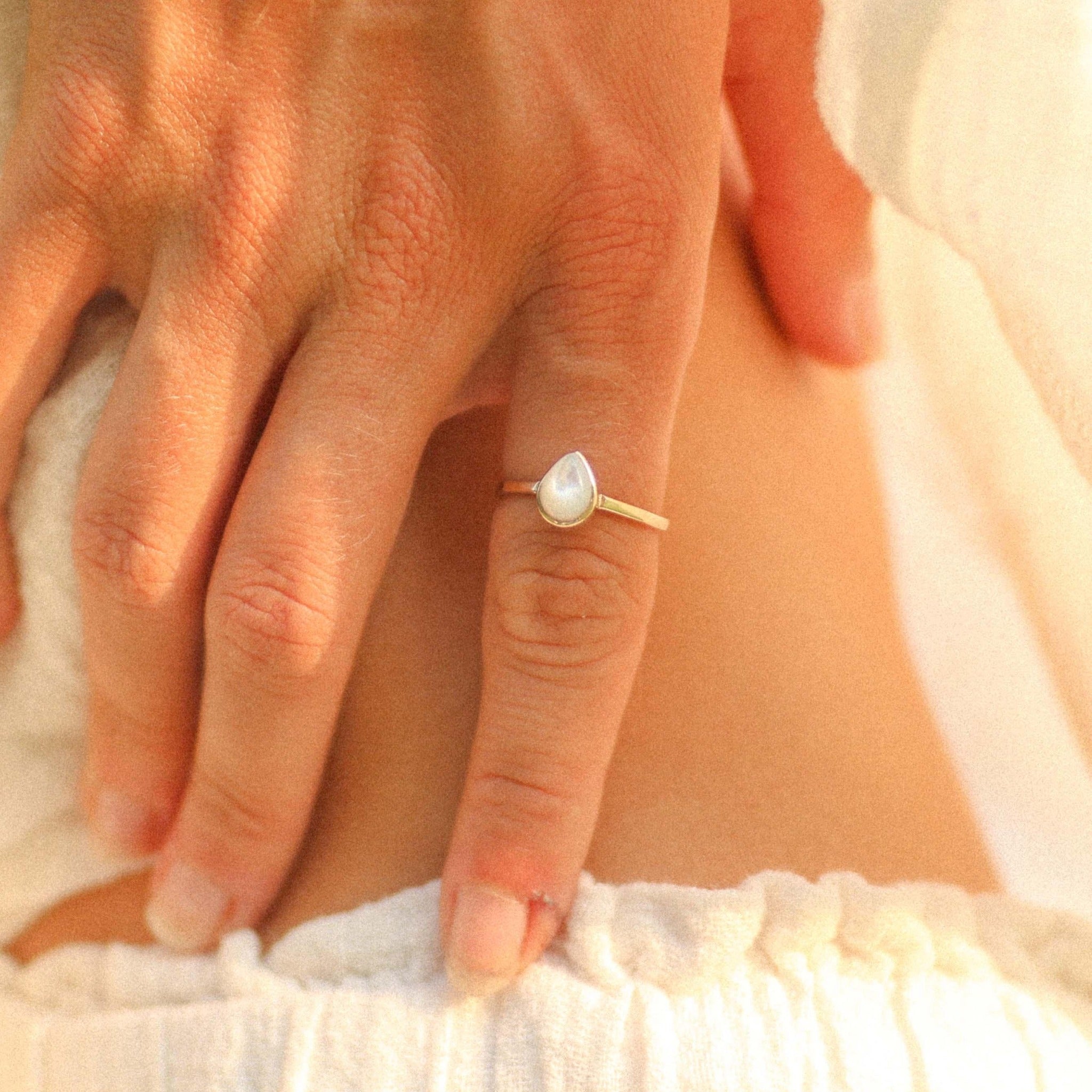 Gold June Birthstone Ring with pear-shaped pearl bieng worn as a meaningful June birthstone jewellery gift for her