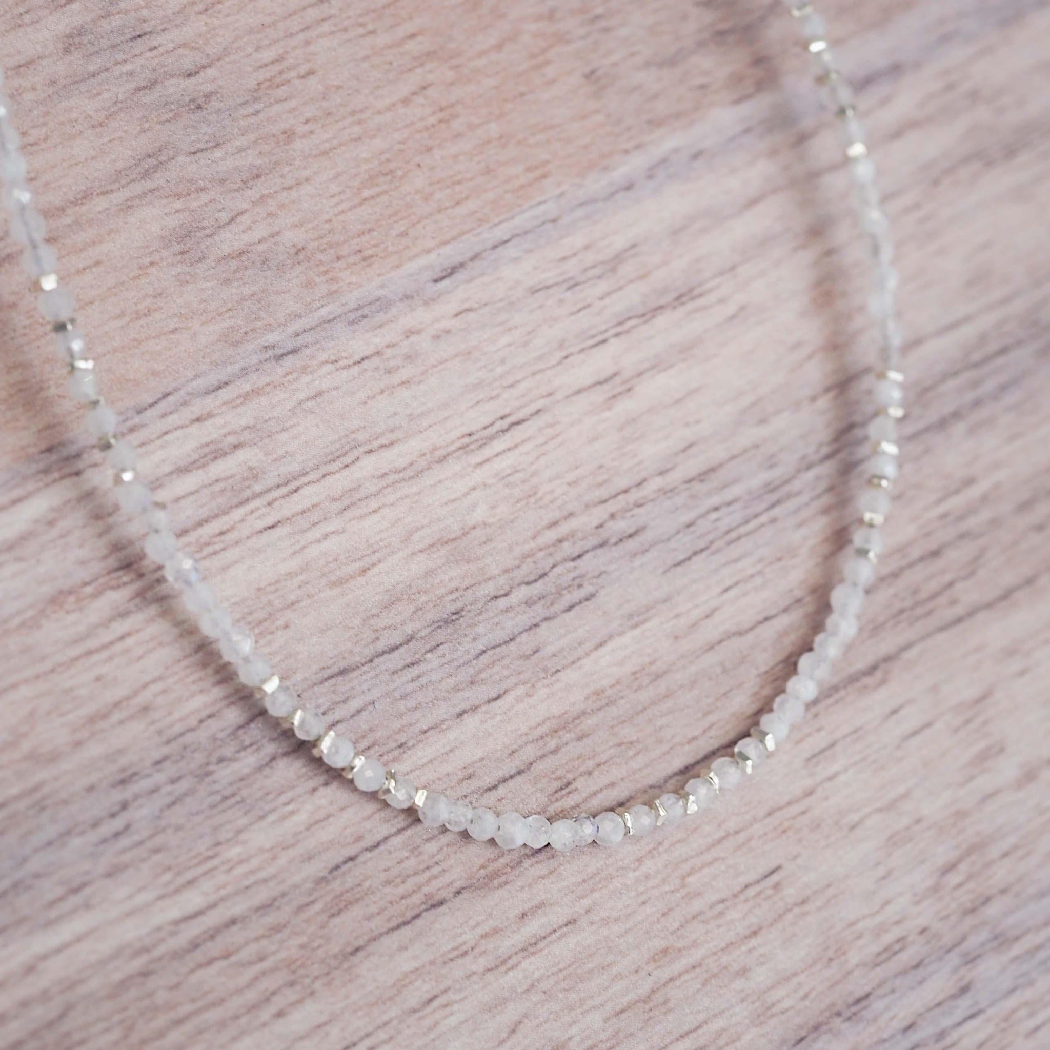 sterling silver Necklace with natural rainbow moonstone beads on a wooden surface