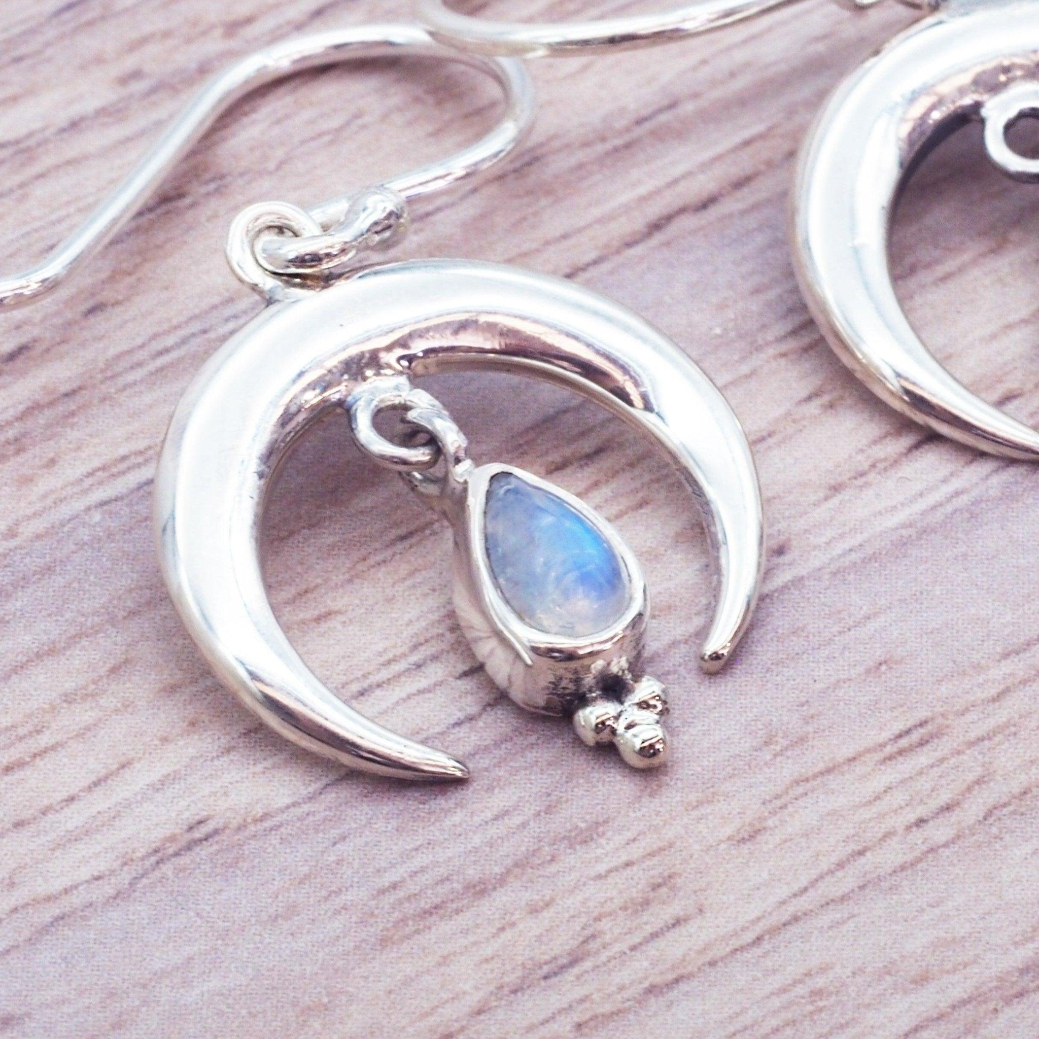 Silver earrings with moonstone on a wooden surface