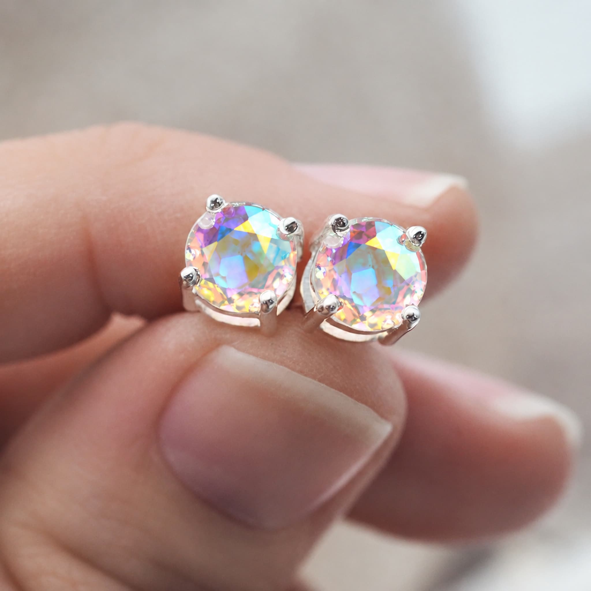 Mystic quartz rainbow stud earrings held in the hand