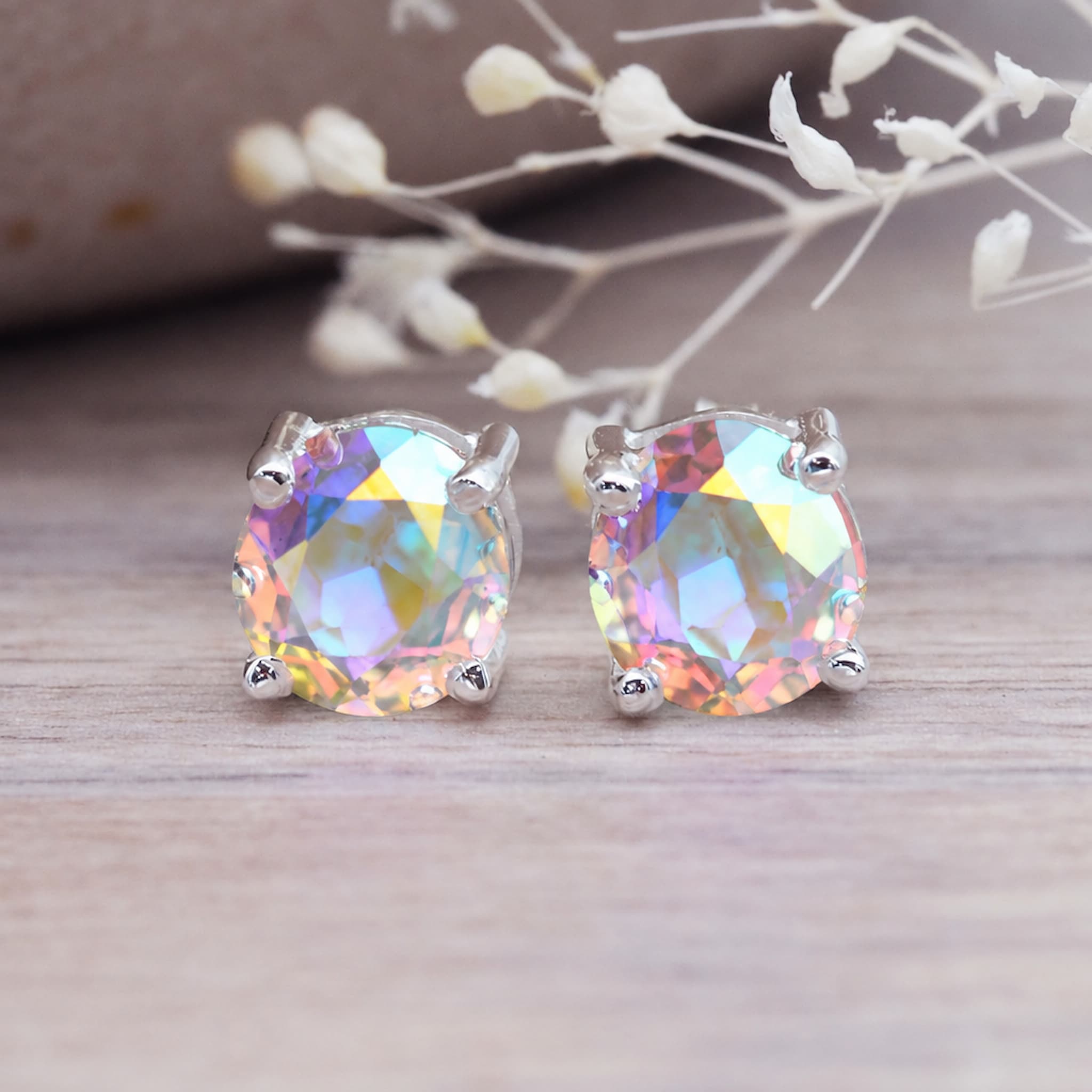 Mystic quartz rainbow stud earrings on a light wooden surface