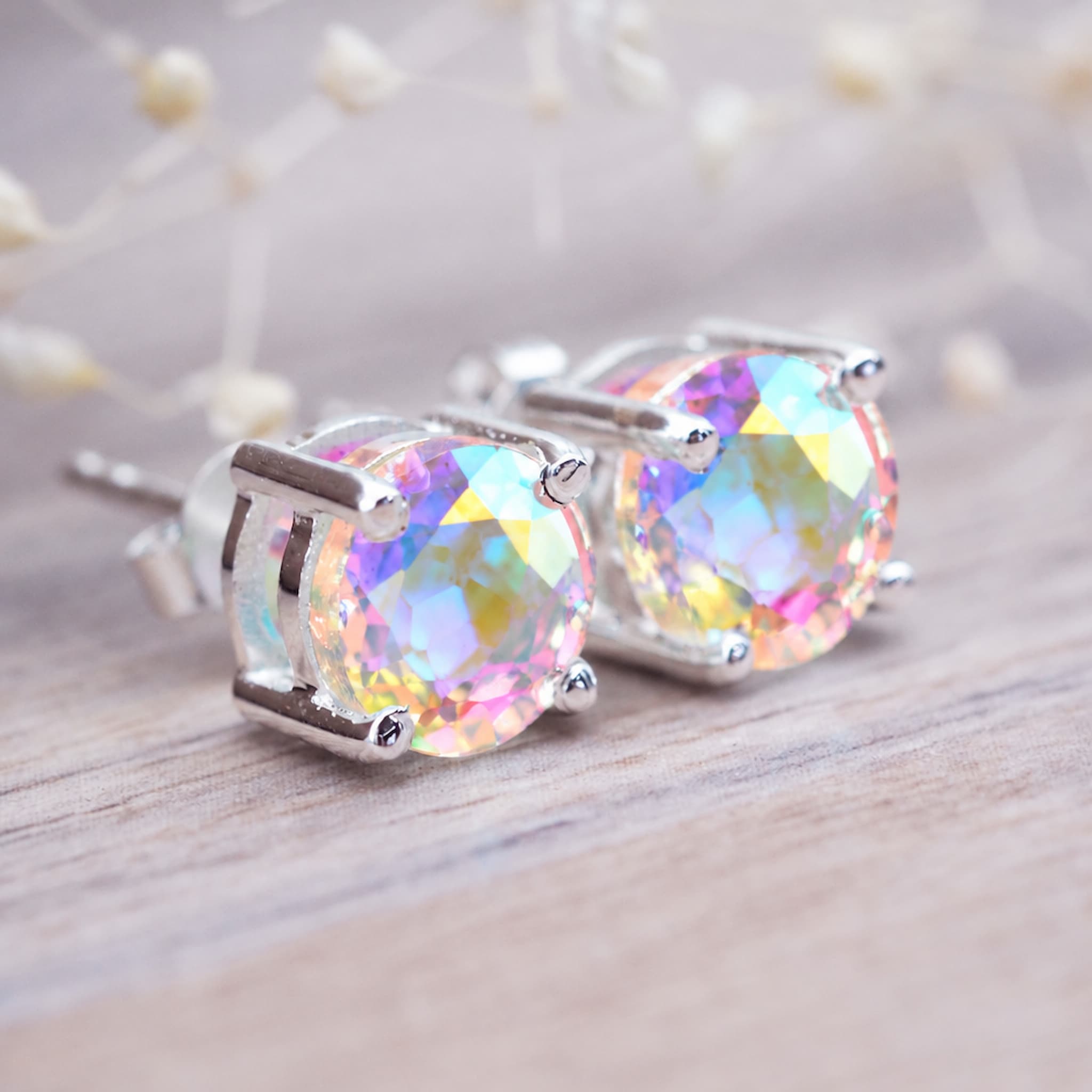 Mystic quartz rainbow studs in sterling silver claw settings on light wood