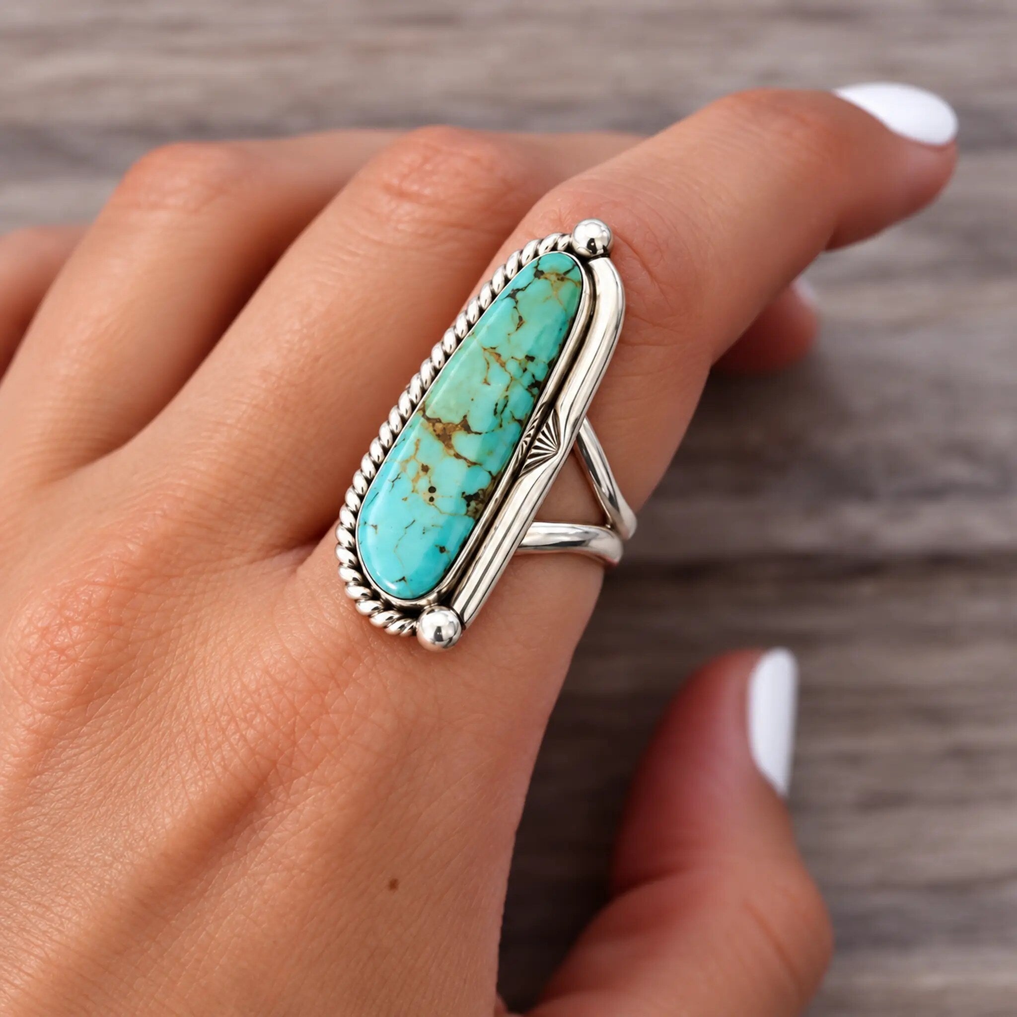 Navajo half twist ring in sterling silver with an elongated teardrop turquoise stone in a rope bezel, worn on the hand