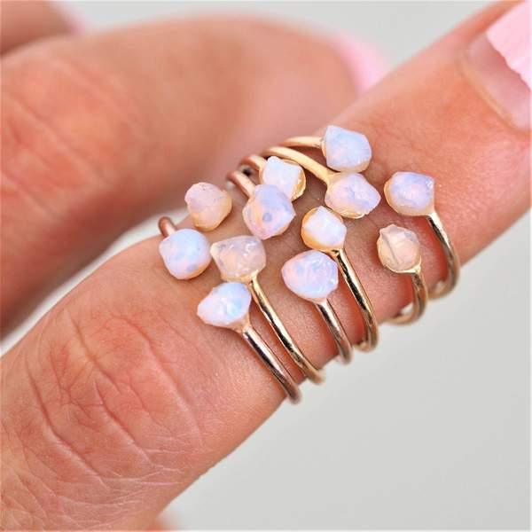 Finger wearing multiple Rose Gold Rings with raw opals - womens opal jewellery