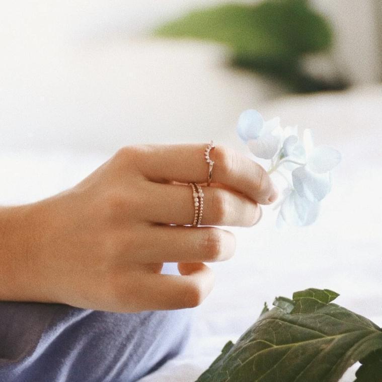 Woman’s hand holding blue flower and wearing Rose Gold Rings - womens rose gold jewellery Australia