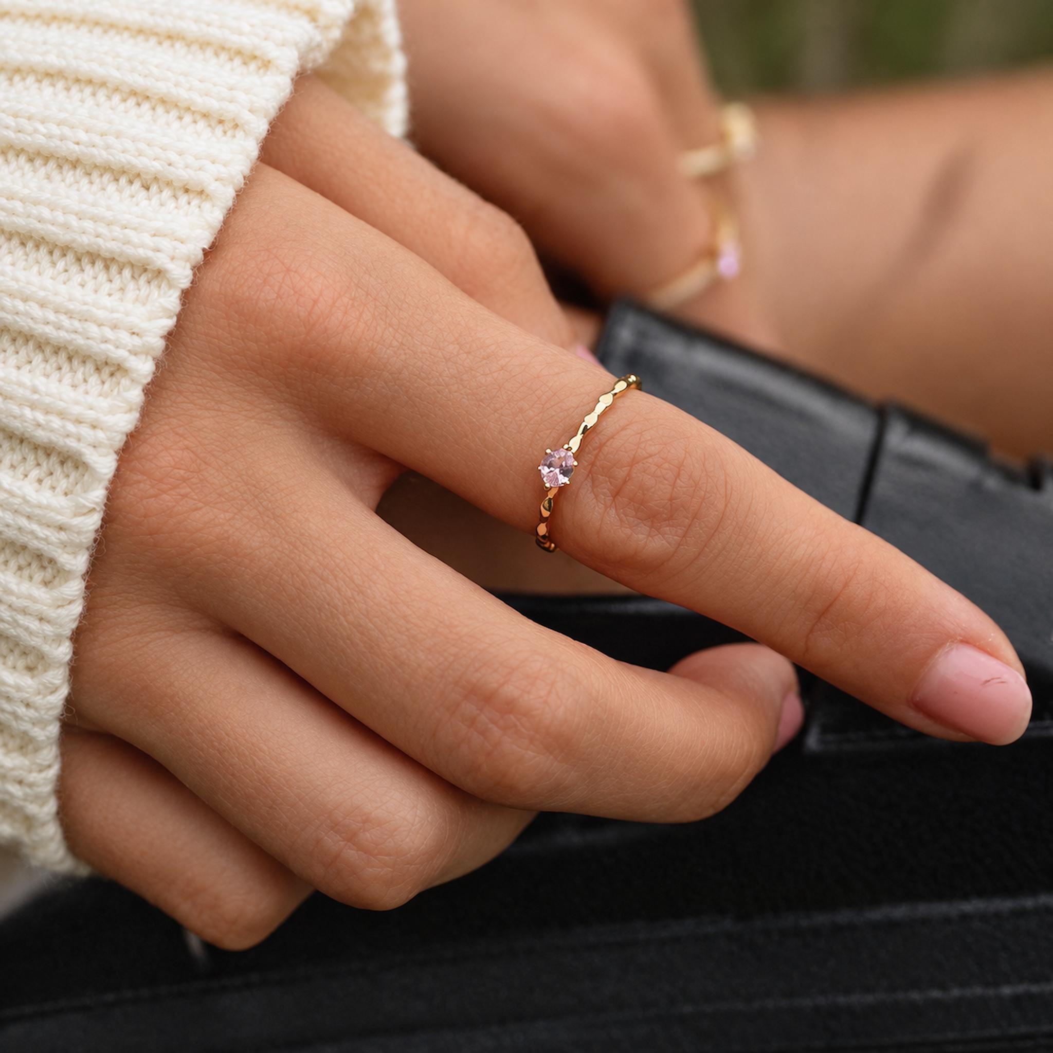 Close-up of a hand wearing a dainty gold rose quartz ring