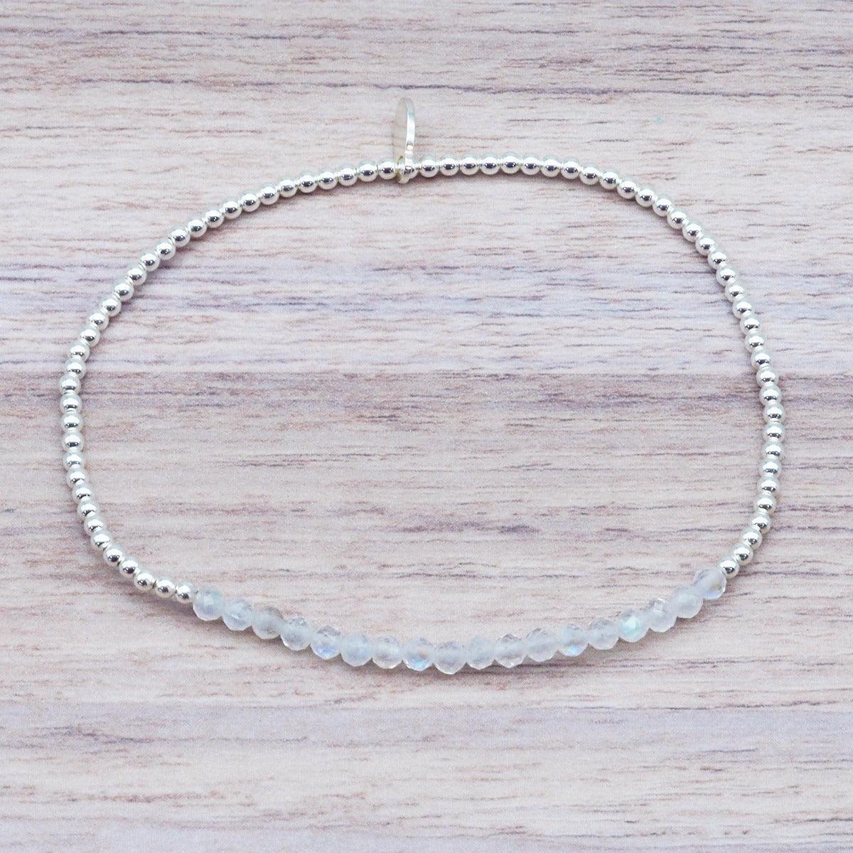 Natural faceted moonstone beaded stretch bracelet with polished 925 sterling silver beads on a light wood surface