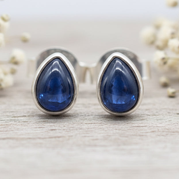Silver Teardrop-shaped blue sapphire gemstone earrings on a white background