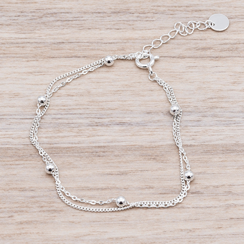 Sterling silver beaded double chain bracelet on a piece of wood