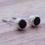 Dainty black Onyx gemstone stud earrings on a wooden surface