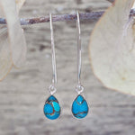 Turquoise teardrop earrings with silver hooks on a natural background