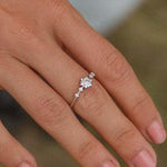 Finger wearing a dainty sterling silver ring with a delicate snowflake celestial cubic zirconia gemstone design