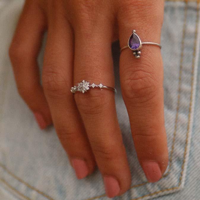 womans hand wearing two boho rings, a sterling silver cubic zirconia dainty celestial design ring and a silver amethyst ring