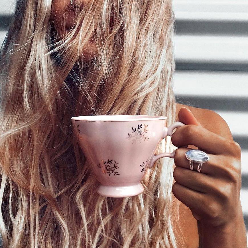 Woman holding a pink tea cup wearing double band moonstone ring by indie and harper Australia 