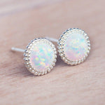 Opal stud earrings with silver bezels on a skin background