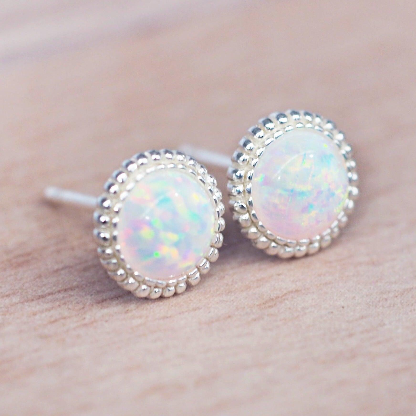 Opal stud earrings with silver bezels on a skin background