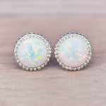 Pair of sterling silver opal stud earrings on a light pink background