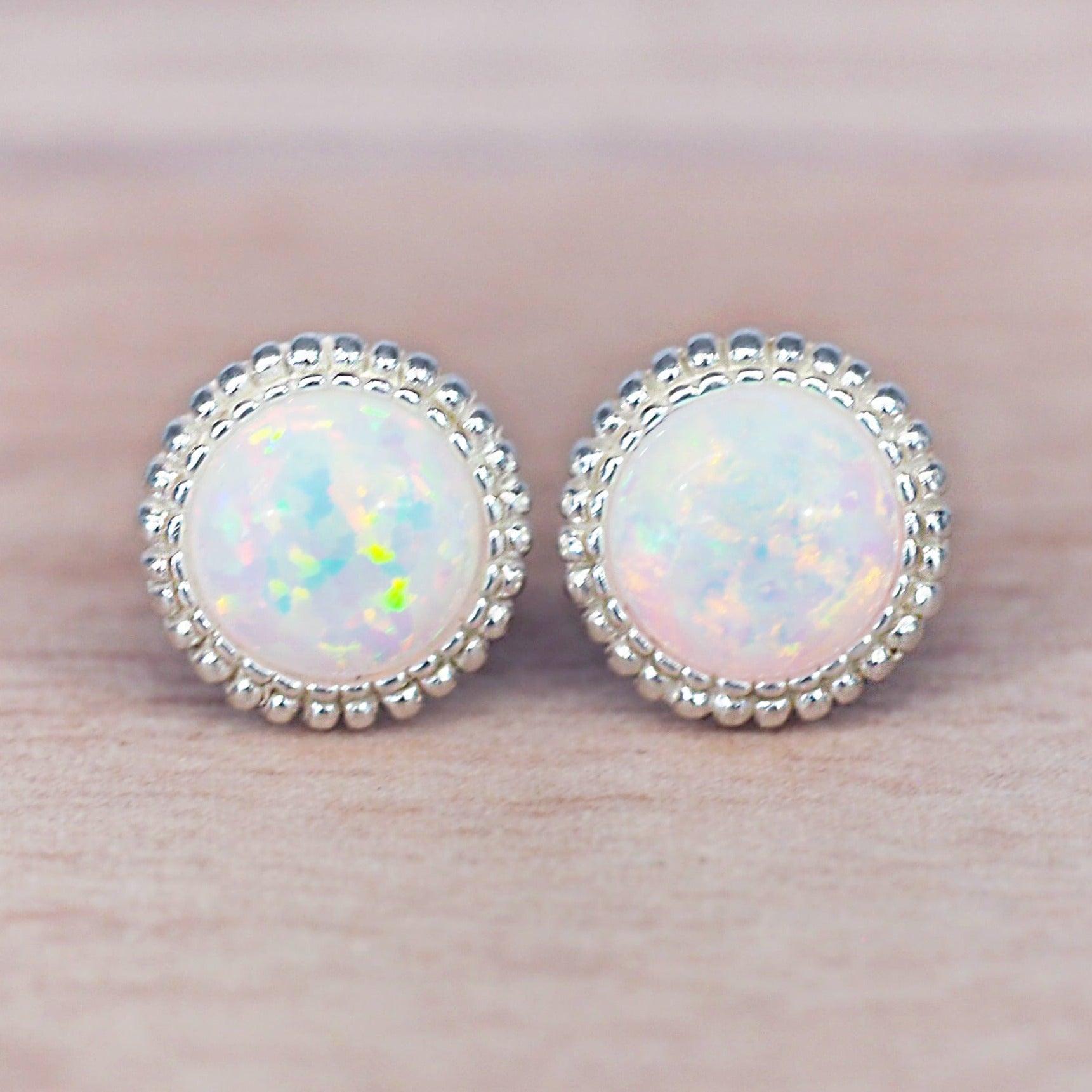 Pair of sterling silver opal stud earrings on a light pink background