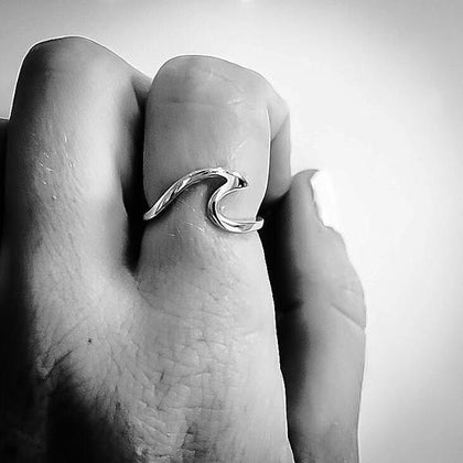 sterling Silver wave ring on a finger against a plain background
