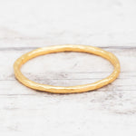 Gold stacker ring on a light wooden surface
