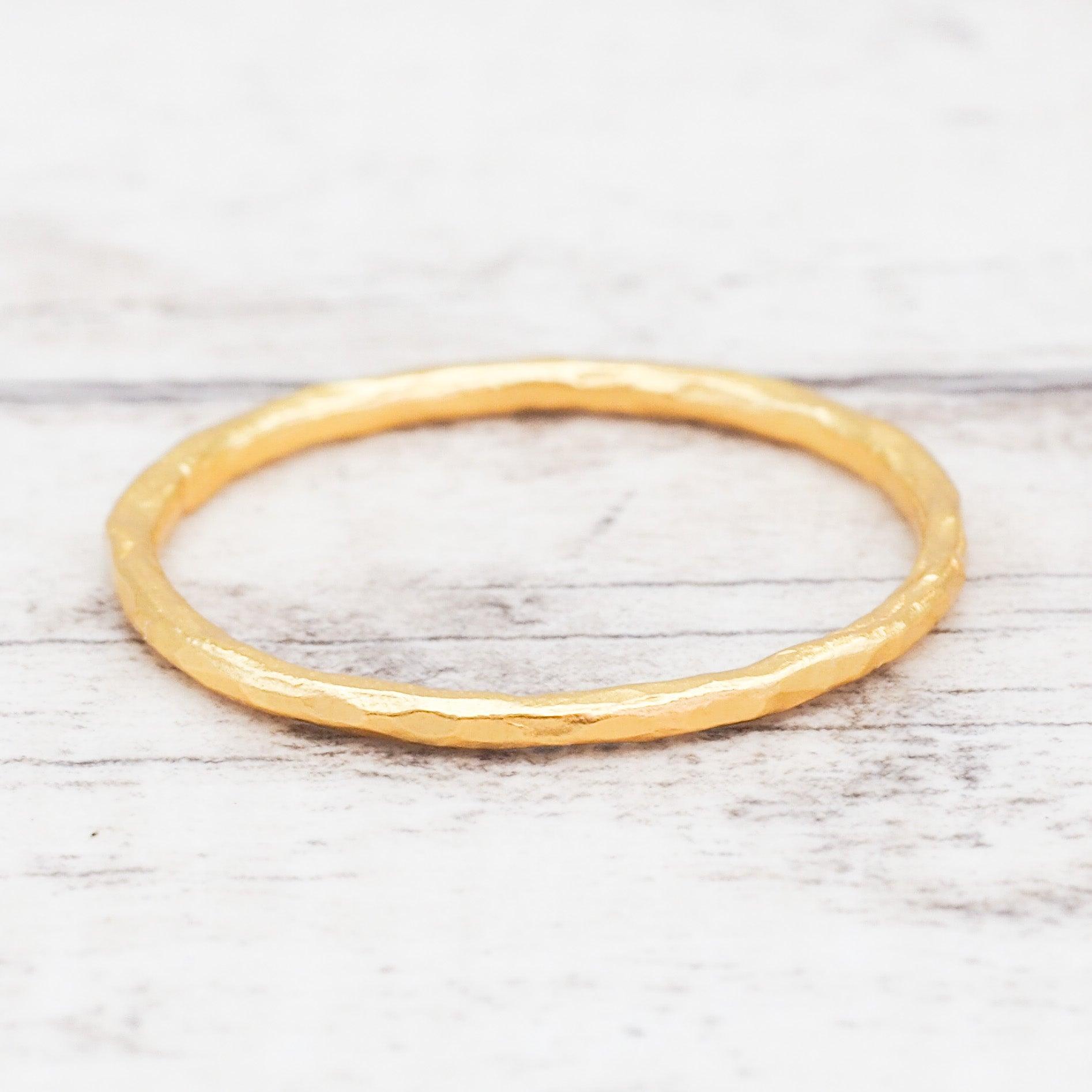 Gold stacker ring on a light wooden surface