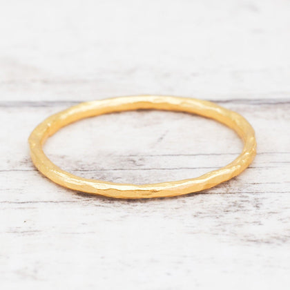 Thin Hammered Gold stacker ring on a light wooden surface