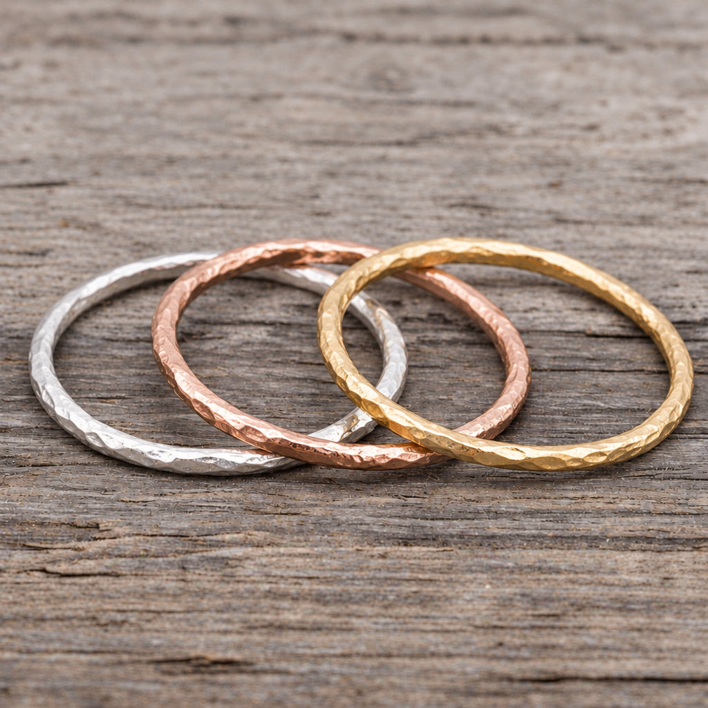 Gold, rose gold and sterling silver hammered stacker rings on a wooden surface