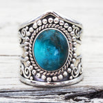 Silver ring with a blue stone on a wooden surface